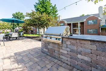 a brick patio with a barbecue grill and a table and chairs